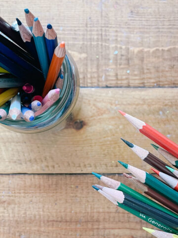 A hand holding colored pencils.