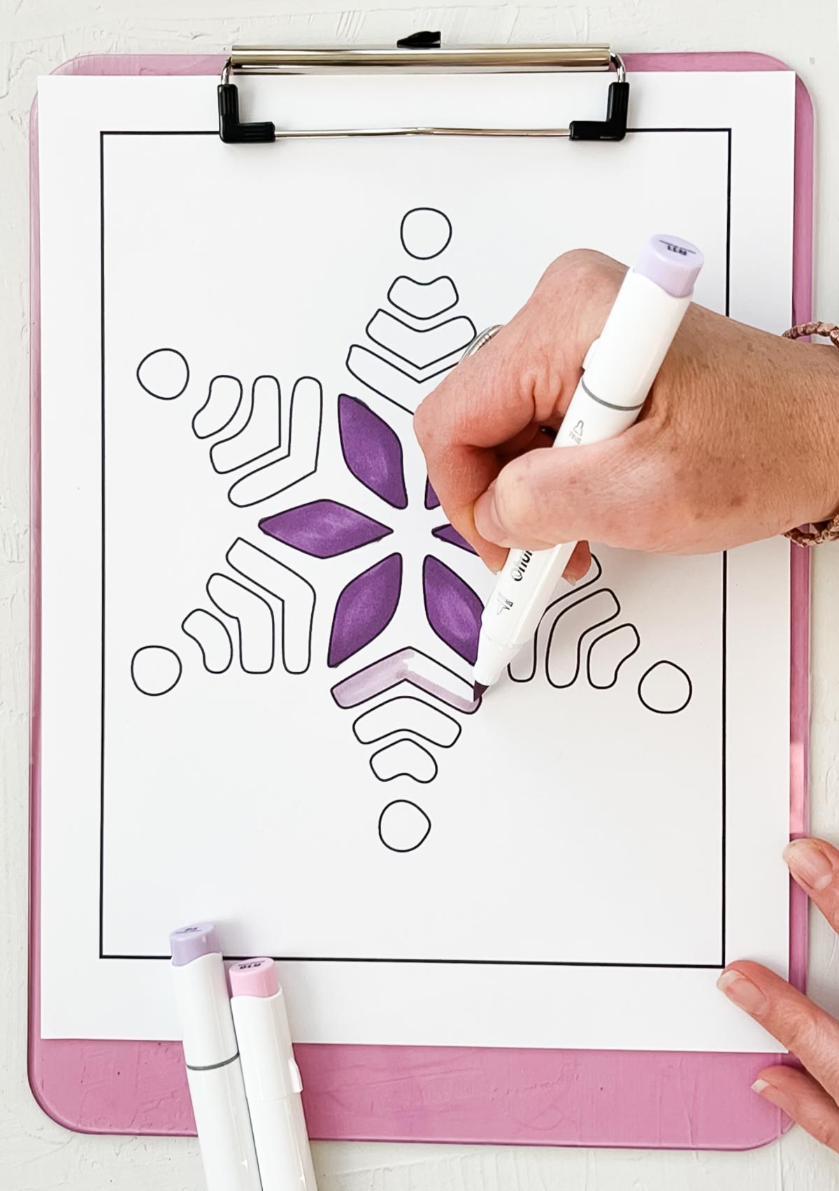 Snowflake coloring page being filled in with a purple marker.