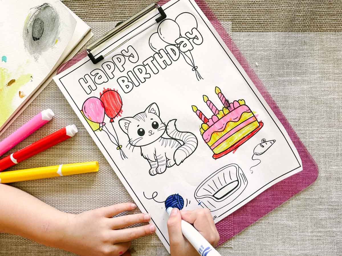 Happy birthday coloring page being colored by a child's hands.