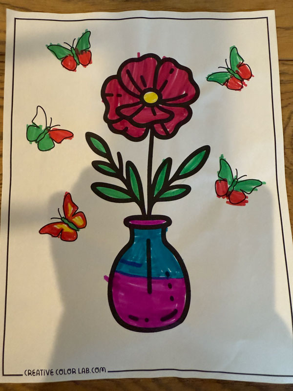 A flower coloring page colored using a marker.